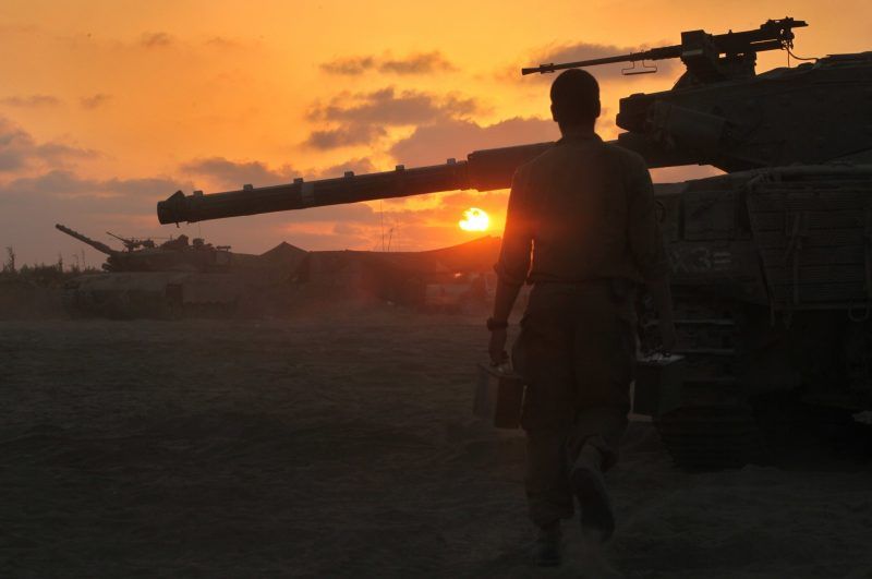 An Israeli soldier walks past a Merkava tank along the border between Israel and the Hamas-controlled Gaza Strip after returning from combat in the Palestinian enclave. (Gil Cohen-Magen / AFP/Getty Images)