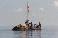 A team of Philippine Navy personnel and three congressmen from the House committee on inter-parliamentary relations and diplomacy lands at the tiny rock of Scarborough Shoal bearing the Philippine flag that was earlier planted by Filipino fishermen. (JESS YUSON/AFP/GETTY IMAGES)