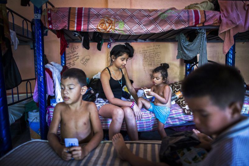  Siblings Luis Danny Pérez, 12-year old Naamá Pérez and Kimberly Julieth Medina, play cards with another child fleeing violence, Anthony Douglas Ponce Barahona, 3, in the shelter's women's dormitory. Credit Katie Orlinsky for The New York Times 