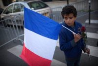 Un niño lleva la bandera francesa y una rosa cerca del Bataclan, la sala de conciertos donde hombres armados mataron a 89 personas. "Golpearon el corazón de París", dijo un trabajador. Credit Pierre Terdjman para The New York Times.