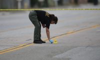 A law enforcement officer picks up a shell casing near the location where the suspects in the shooting at the Inland Regional Center were killed on Dec. 4 in San Bernardino, Calif. (Joe Raedle/Getty Images)