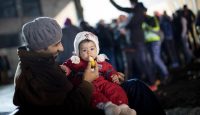 A Syrian refugee feeds his daughter in Berlin on December 21, 2015, two days after a new UN resolution brought renewed hope for peace. Photo by KAY NIETFELD/AFP/Getty Images)