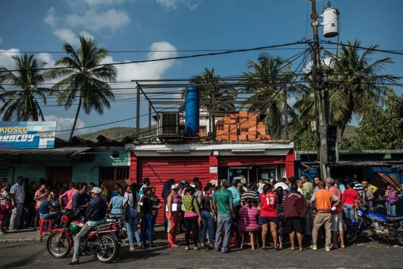 Personas esperan en fila frente a una tienda de comestibles en Puerto Cabello, Venezuela. Meridith Kohut para The New York Times