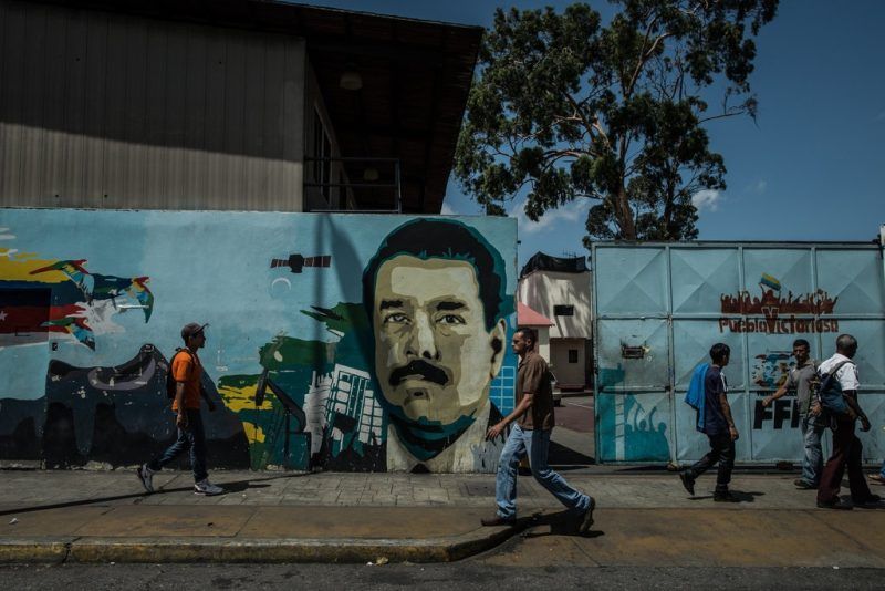 People walk past a mural of President Nicolás Maduro in Caracas. Meridith Kohut for The New York Times