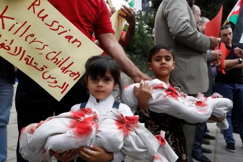Children hold dolls symbolizing dead babies during in a sit-in in solidarity with the people of Aleppo and against Russia's support of the Syrian regime, in front of the Russian embassy in Amman, Jordan, May 3, 2016. The placard reads, "Russian are baby killers". REUTERS/Muhammad Hamed
