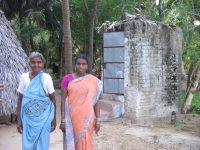 A Tamil woman and her mother-in-law in front of their toilet whose roof caved in - hence the thatch. FAL