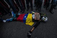 Un manifestante protesta frente a un bloqueo policial con carteles que dicen: "Balas no. Comida si" y "Venezuela vive en una dictadura", en noviembre de 2016 en Caracas. Credit Meridith Kohut para The New York Times