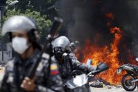 Police move away from the flames after an explosion during clashes with anti-government protesters in Caracas on July 30. (Ariana Cubillos/AP)