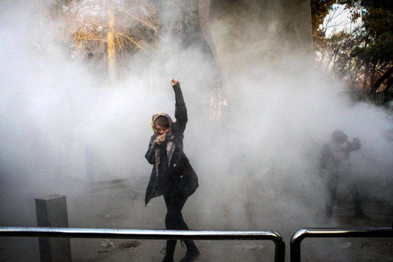 A woman dodged tear gas at Tehran University on Saturday, the third day of unauthorized protests in Iran. Credit via Associated Press