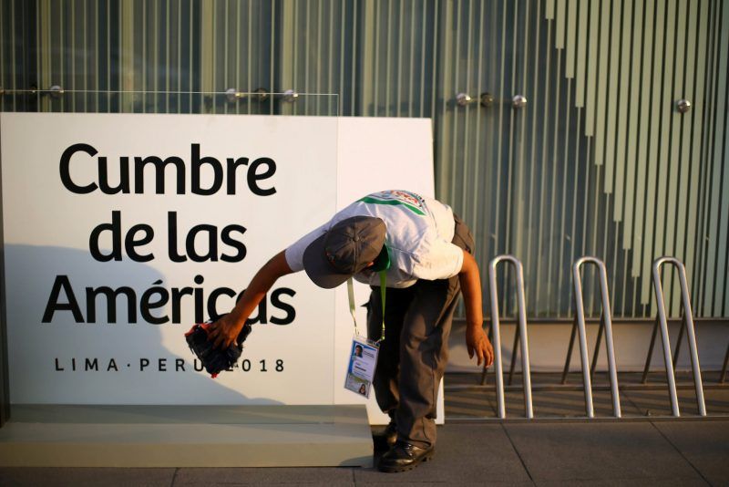 Una mujer limpia una señalización de la Cumbre de las Américas en Lima, Perú, el 10 de abril de 2018. Credit Iván Alvarado/Reuters 