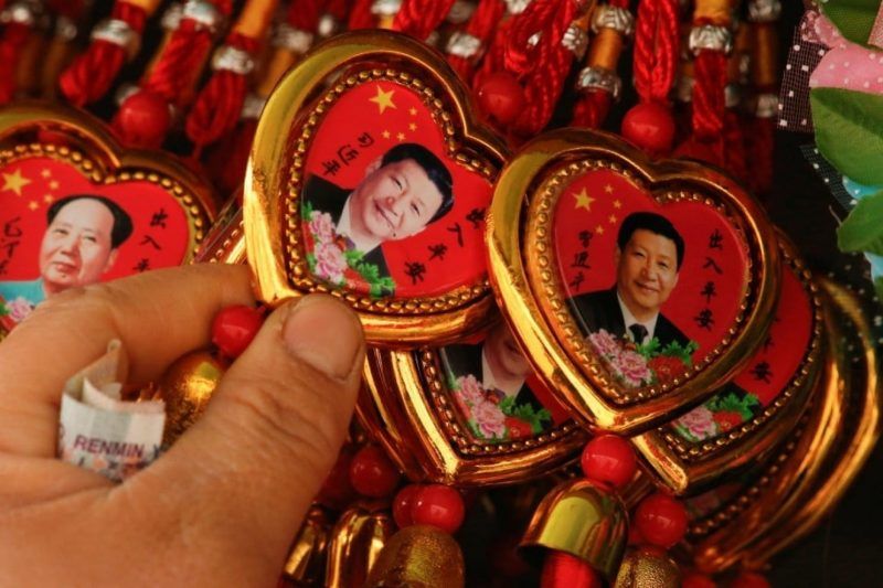 A woman selects a souvenir necklace with a portrait of Chinese President Xi Jinping at a stall in Tiananmen Square in Beijing, China. Feb. 26, 2018. (Thomas Peter/Reuters)