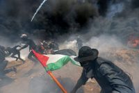 Manifestantes palestinos escapan del fuego y el gas lacrimógeno que lanzan soldados. Credit Ibraheem Abu Mustafa/Reuters