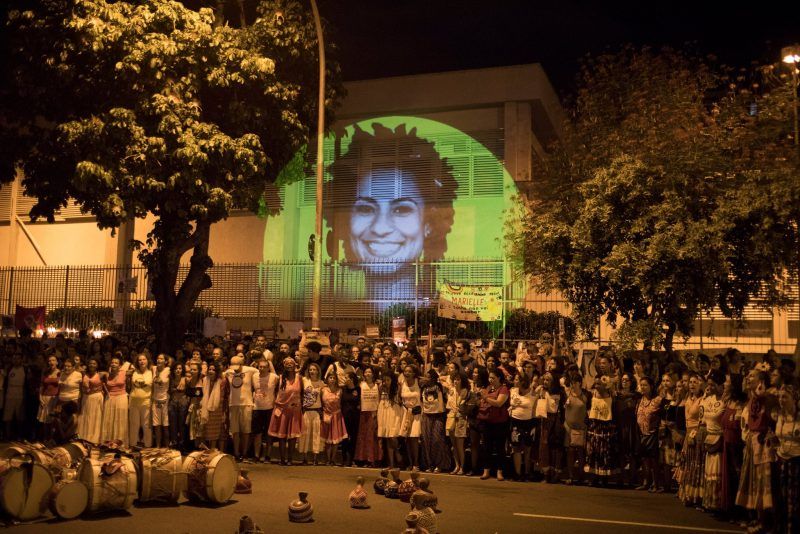  Con una imagen de la concejala Marielle Franco proyectada en un muro, algunos habitantes de Río de Janeiro se reunieron en abril para manifestarse en el sitio donde Franco y su conductor, Anderson Pedro Gomes, fueron asesinados en marzo. Credit Leo Correa/Associated Press 