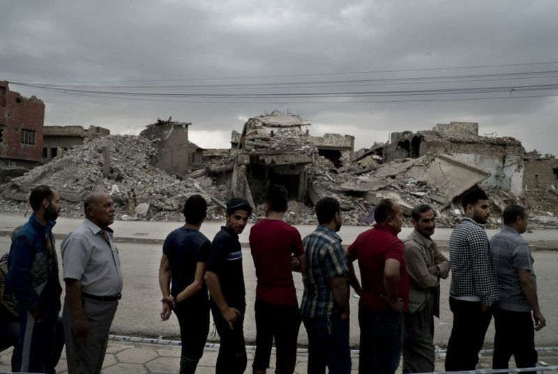 Iraqis in Mosul waited to vote on May 12 next to a building in ruins from the battle to oust Islamic State militants from their city. (Maya Alleruzzo/AP)