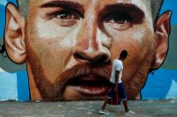 En Barcelona, el 12 de julio de 2018, un hombre pasa frente a un grafiti de Lionel Messi. Credit Pau Barrena/Agence France-Presse — Getty Images