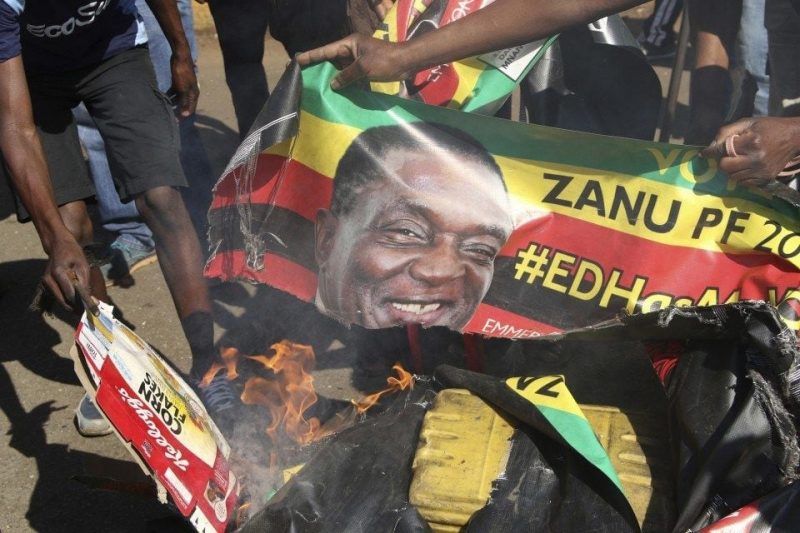 Opposition supporters burn posters of Zimbabwean President Emmerson Mnangagwa while protesting election results in Harare on Aug. 1. (AP)