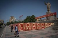 KASGHAR CITY, KASHGAR, XINJIANG, CHINA - 2017/07/08: A Uyghur woman walks pass a statue of Mao Zedong in the People's Park in Kashgar city, northwestern Xinjiang Uyghur Autonomous Region in China. (Photo by Guillaume Payen/SOPA Images/LightRocket via Getty Images)
