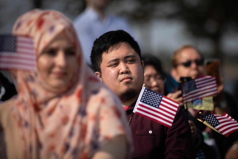 Drew Angerer/Getty Images. New US citizens hold American flags during a naturalization ceremony at Liberty State Park, Jersey City, New Jersey, October 2, 2018
