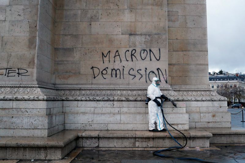 A worker prepares to clean graffiti reading “Macron resignation” on the Arc de Triomphe the day after a French protest of plans to increase the taxes on gasoline and diesel fuel. Credit Thibault Camus/Associated Press