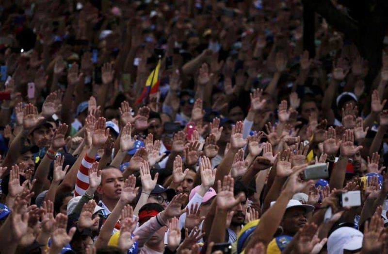 Protesters demanding Venezuelan President Nicolás Maduro’s resignation raise their hands during the symbolic swearing-in of Juan Guaidó, head of the opposition-run congress who declared himself interim president of Venezuela, in Caracas, Venezuela, on Wednesday. (Fernando Llano/AP)