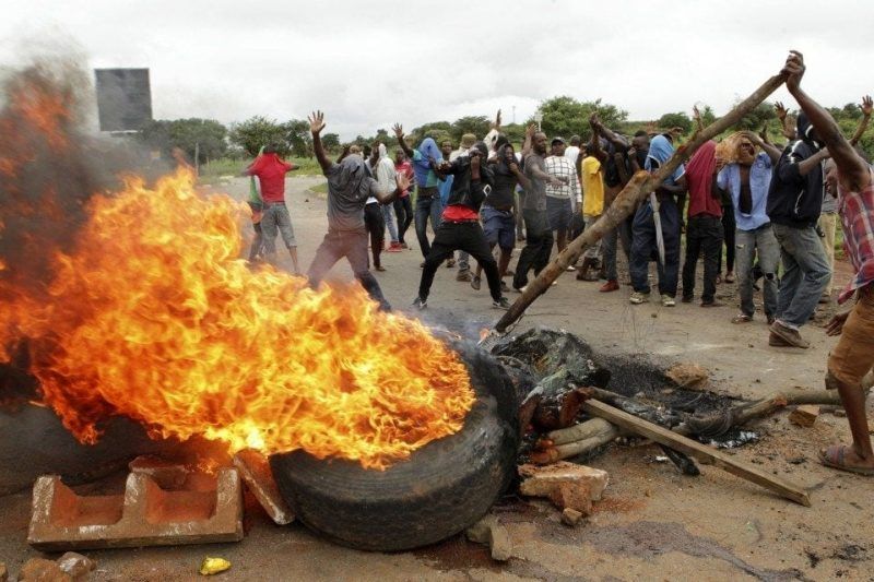 Protesters gather near a burning tire during a demonstration over the hike in fuel prices in Harare, Zimbabwe, on Jan. 15. (AP)