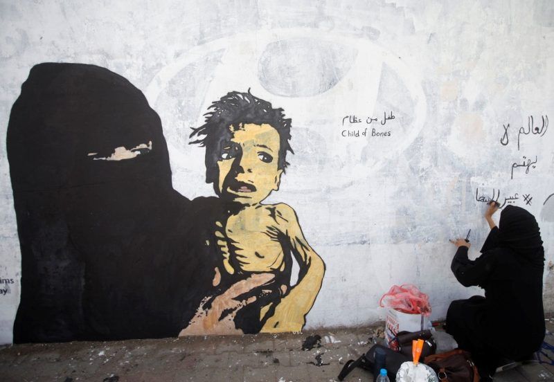 A Yemeni woman writes on a mural about children and women suffering in the time of war in Sanaa, Yemen, in February. (Mohamed al-Sayaghi/Reuters)