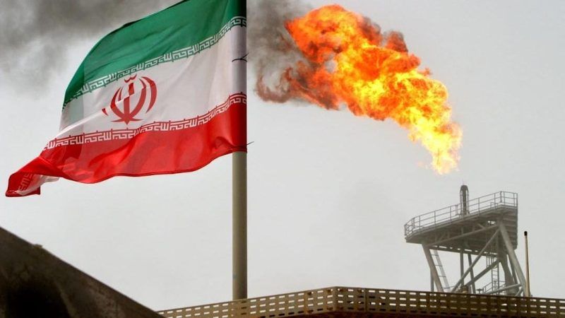 A gas flare on an oil production platform in the Soroush oil fields is seen alongside an Iranian flag in the Persian Gulf, Iran, 25 July 2005. OPEC-OIL/ REUTERS/Raheb Homavandi
