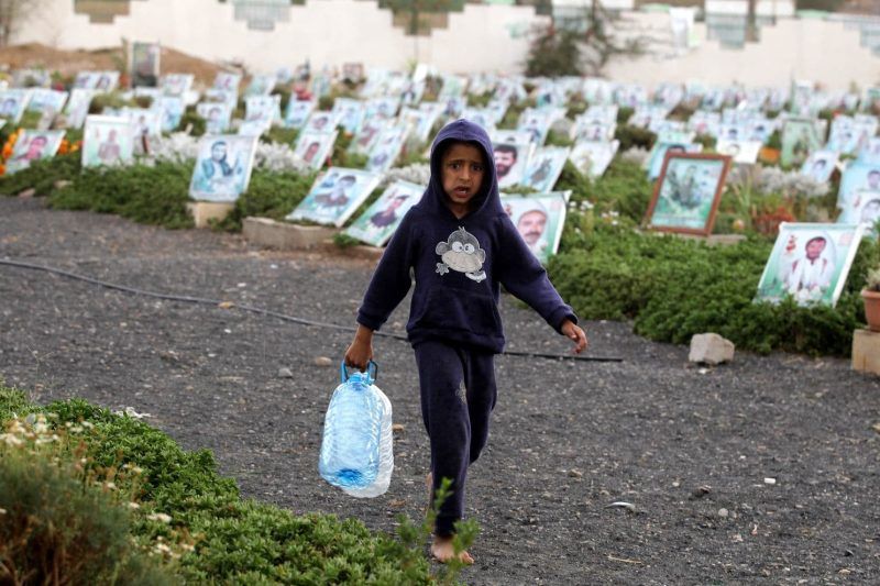 A Yemeni child holding empty bottles walks past portraits on the graves of Yemenis killed in the country's ongoing conflict at a cemetery in Sanaa, Yemen, on April 17. (Yahya Arhab/EPA-EFE/REX)