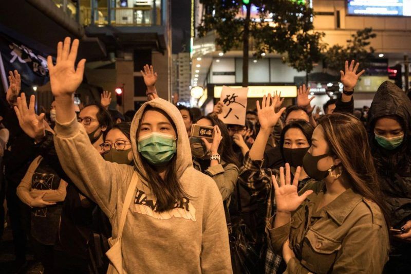 Anti-government protesters chant slogans and wave flags at police Monday after gathering in front of an entrance to Hong Kong Polytechnic University, where a small number of protesters are held up inside. (Chris Mcgrath/AFP/Getty Images)