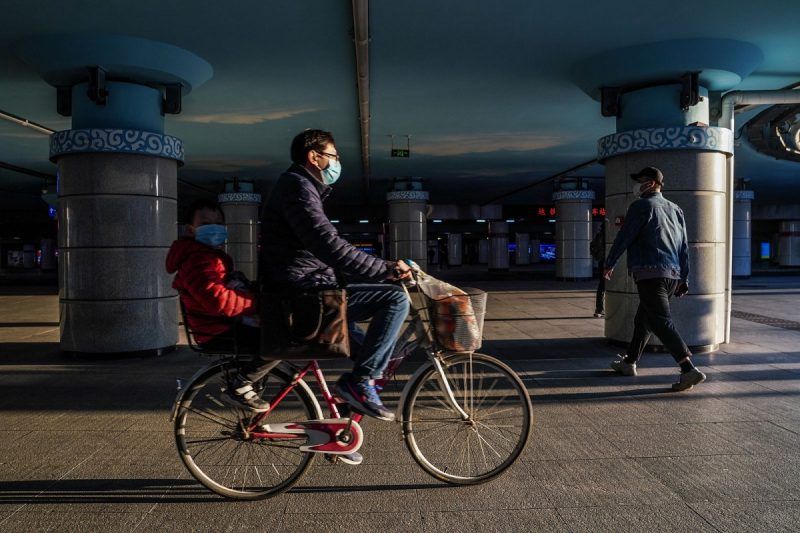 Lintao Zhang/Getty Images. A Chinese man and a child wearing protective masks on a bike, Beijing, China, March 27, 2020