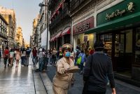 Una persona que trabaja con un organillero pide unas monedas a los transeúntes de una calle del centro de Ciudad de México a en marzo. Credit Daniel Berehulak para The New York Times
