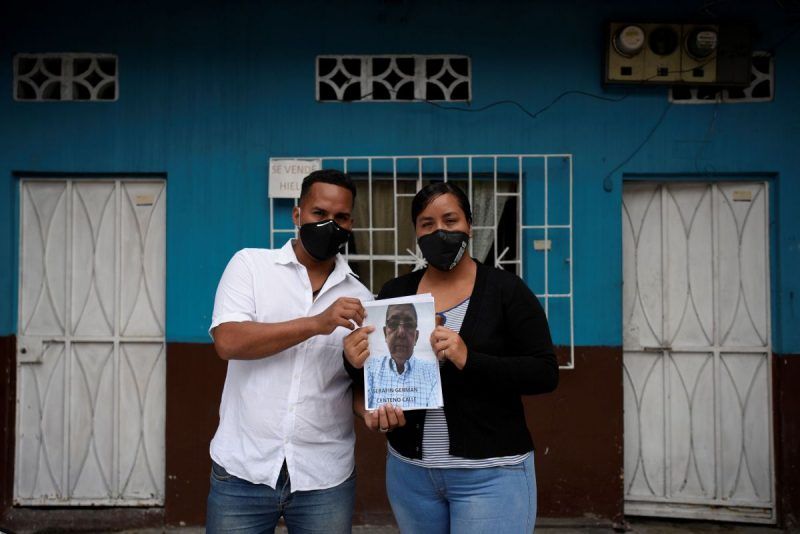 Jimmy Centeno y su hermana Dolores Centeno sostienen una fotografía de su padre, Cerafin Centeno, cuyo cuerpo no han podido encontrar desde que murió hace dos meses por COVID-19, en Guayaquil, Ecuador. La imagen es del 19 de mayo de 2020. (Santiago Arcos)