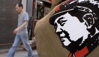 A man walks past a bag printed with the portrait of China's revolutionary leader Mao Tse-tung on display outside a shop in Hong Kong. Photo by PHILIPPE LOPEZ/AFP via Getty Images.
