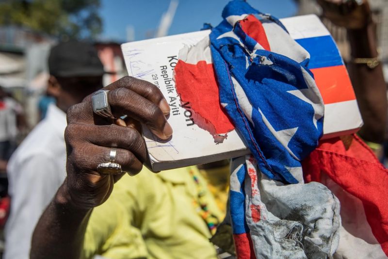 A copy of the Haitian Constitution wrapped in an American flag at a march in Port-au-Prince on Feb. 10. The Haitian president’s supporters and opponents disagree on when his term ends. Credit Valerie Baeriswyl/Agence France-Presse — Getty Images