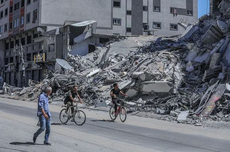 Palestinians ride bicycles past a destroyed building in Gaza City on Tuesday. (Mohammed Saber/EPA-EFE/REX/Shutterstock)