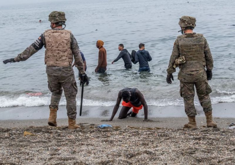 Soldados españoles junto a inmigrantes que han cruzado a nado por la frontera del Tarajal, en Ceuta, este martes.Javier Bauluz
