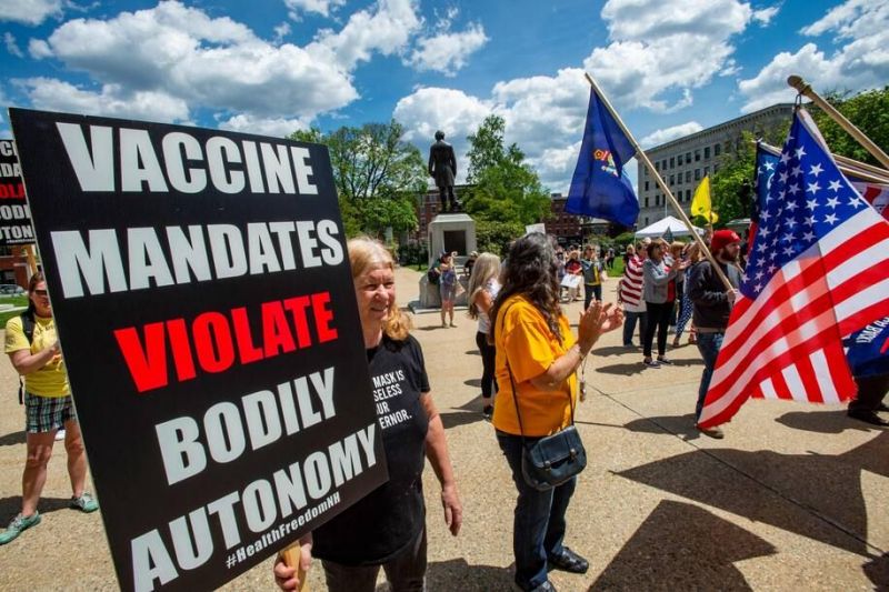 Manifestantes sostienen carteles contra las vacunas en un mitin en Concord, New Hampshire, el 15 de mayo de 2021. (Joseph Prezioso/AFP)