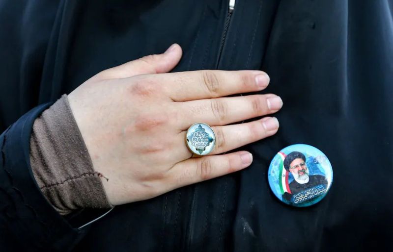 A woman holds her hand to her chest next to a pin bearing the image of Ebrahim Raisi, Iran’s newly elected president, at a rally June 19 in Tehran celebrating his victory. (Atta Kenare/AFP/Getty Images)