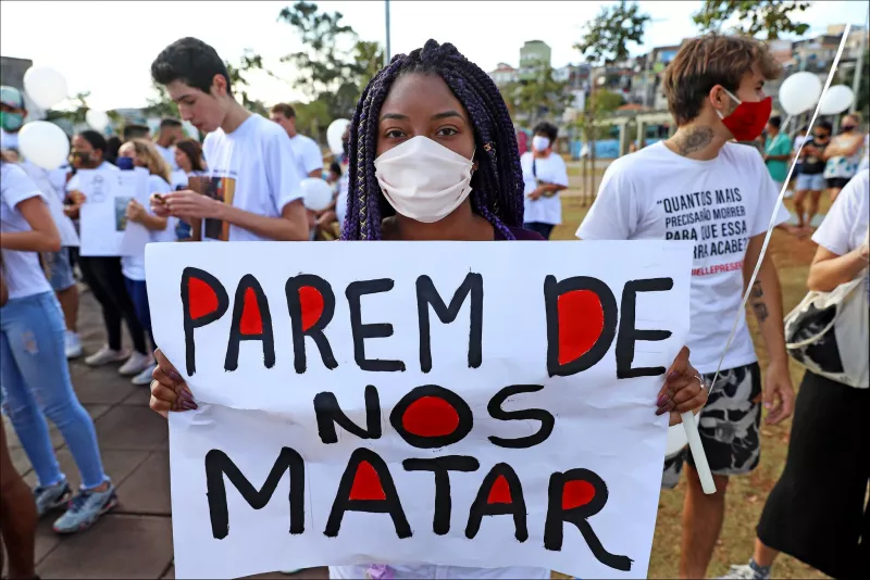A demonstrator holds a sign that reads, “Stop killing us,” at a march in São Paulo, Brazil, protesting the death of Guilherme Silva Guedes, a teenager who was allegedly killed by police. Credit Leo Barrilari/EPA, via Shutterstock