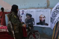 A Taliban fighter looks at Taliban flags and posters of leaders in Kabul on Aug. 25. (AP)