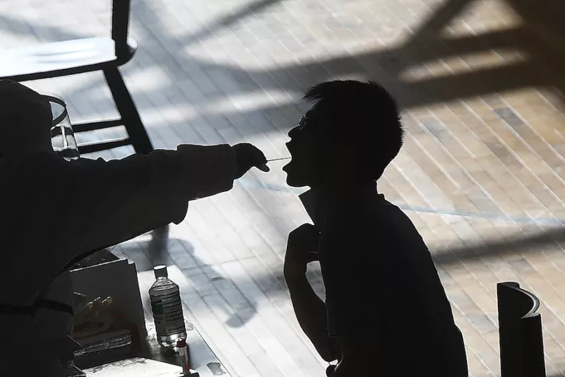 A medical worker takes a swab sample from a worker from the China Star Optoelectronics Technology (CSOT) company in a gym during a round of covid-19 testing in Wuhan in central China's Hubei province on Aug. 5. (Chinatopix via AP) (AP)