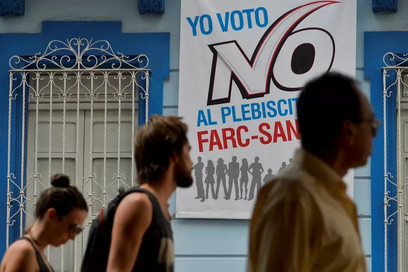 People walk by a placard that reads: ‘I vote for No in the Farc-Santos plebiscite’ in the referendum on the peace agreement in Cali, Colombia, in 2016 © Luis Robayo/AFP via Getty Images