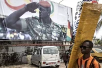 A sunglasses seller walks past a billboard showing coup leader Col. Mamady Doumbouya in Conakry, Guinea, on Sept. 11. Doumbouya’s special forces seized President Alpha Condé in a Sept. 5 coup, promising to form a unity government. (John Wessels/AFP/Getty Images)