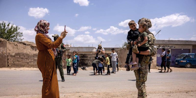 A local woman photographs a US soldier with her children while on patrol near the Turkish border in northeastern Syria. Photo by John Moore/Getty Images. 