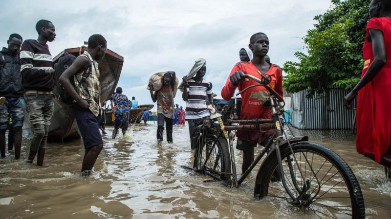 Displaced people walk with their belongings in a flooded area after the Nile river overflowed after continuous heavy rain which caused thousands of people to be displaced in Bor, central South Sudan, on 9 August 2020. Akuot Chol / AFP