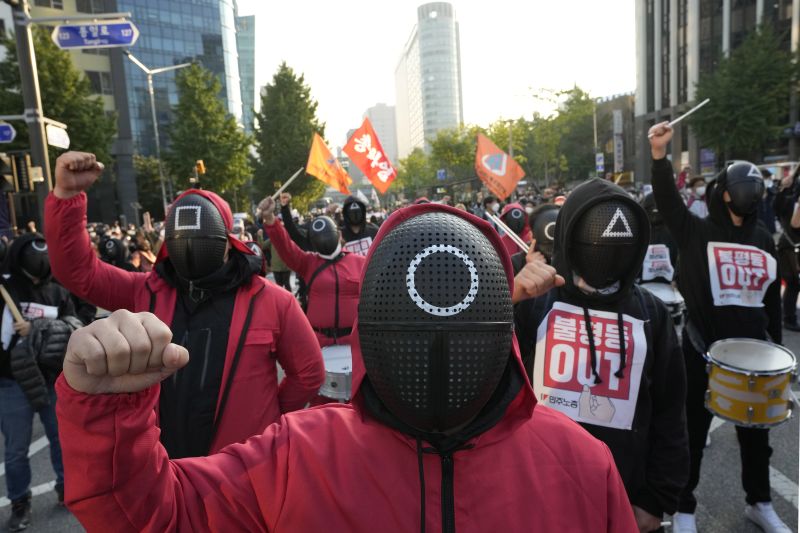 Miembros de la Confederación de Sindicatos de Corea del Sur, con máscaras y disfraces inspirados en la serie de Netflix 'El juego del calamar', durante una manifestación para exigir seguridad laboral en Seúl, Corea del Sur, el 20 de octubre de 2021. (AP Photo/Ahn Young-joon)
