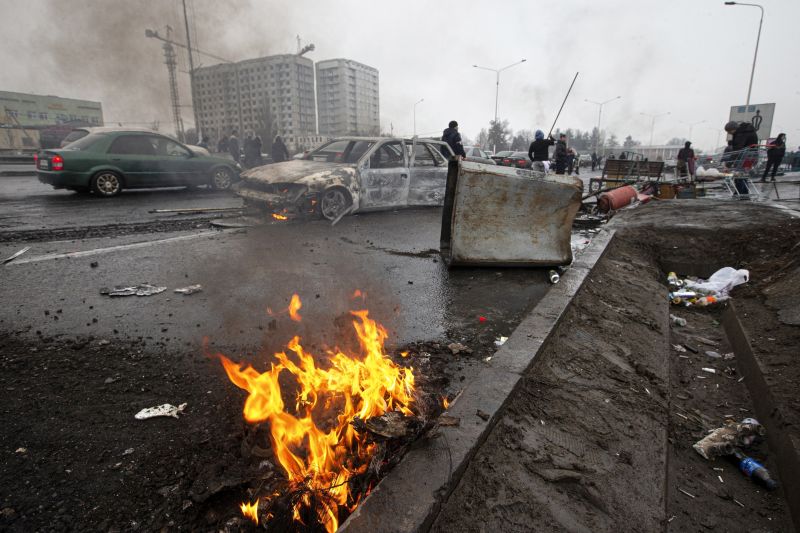People walk past cars burned during clashes between protesters and government forces on a street in Almaty, Kazakhstan, on Jan. 7. (Vasily Krestyaninov/AP)