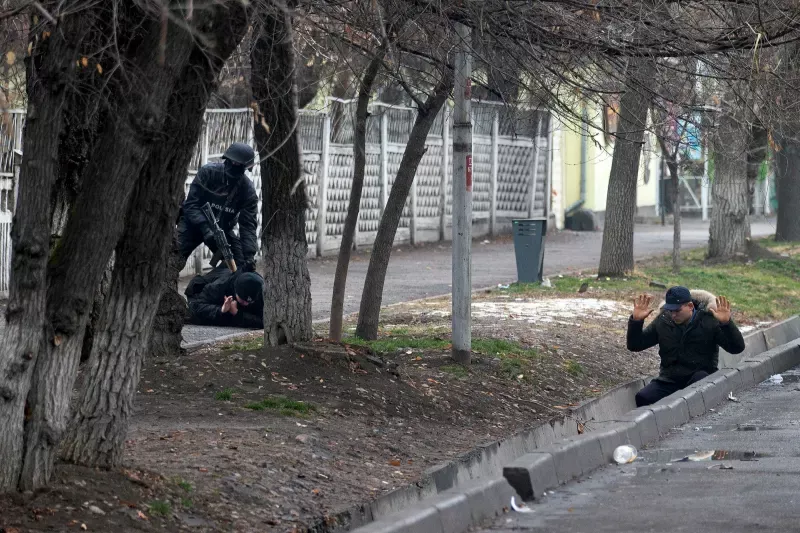 An armed police officer detains two protesters after clashes in Almaty last week © Vasily Krestyaninov/AP