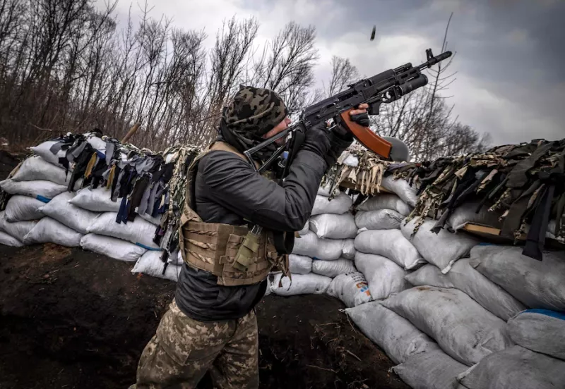A Ukrainian serviceman shoots with an assault rifle from a trench at the front line east of Kharkiv on March 31. (Fadel Senna/AFP/Getty Images)