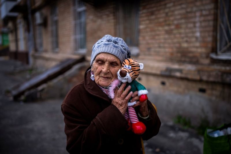Melaniya Kovalenko, 90, hugs a donated toy doll outside her home in Bucha, Ukraine, on April 18. She said she intends to give the toy to her grandchildren. (Emilio Morenatti/AP)